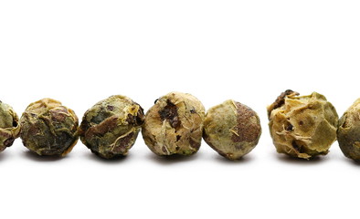 Dry green pepper pile, macro peppercorn isolated on white