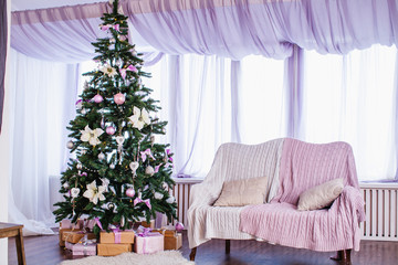 a Xmas tree with gifts under it and a sofa