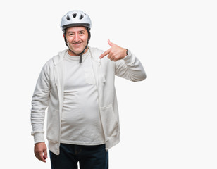 Handsome senior cyclist man wearing bike helmet over isolated background with surprise face pointing finger to himself