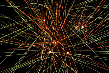 Closeup of fireworks exploding the in the sky, making abstract colorful lines through the darkness
