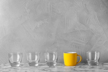 Row of glasses with bright cup on table. Be different