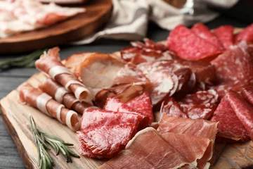 Photo sur Plexiglas Viande Planche à découper avec différents produits de viande en tranches servis sur table