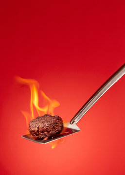 Grilling Burger Against Red On Spatula