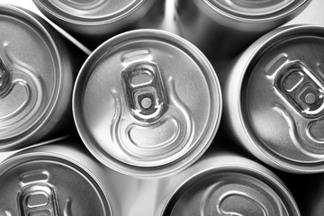 Aluminum cans with cold beverage as background, top view