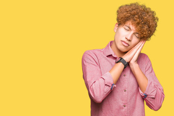 Fototapeta premium Young handsome business man with afro hair sleeping tired dreaming and posing with hands together while smiling with closed eyes.