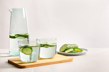 Glasses and jug of fresh cucumber water on table. Space for text