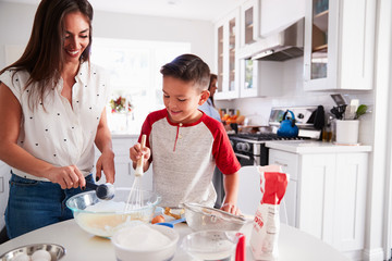 Pre-teen boy making a cake in the kitchen with his mum, close up