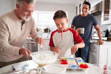 Dad watching his son making cakes with grandad at the kitchen table, close up