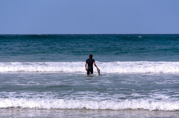 Fototapeta na wymiar A surfer with his board going into the sea