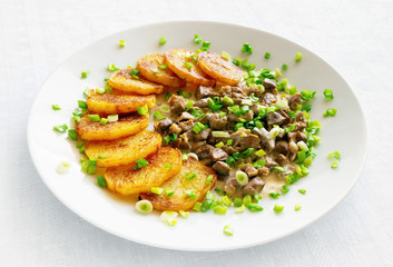 stewed in sour cream chicken offal with fried potato slices decorated with green onion