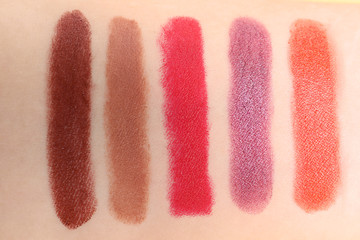 Lipstick swatches on skin as background, closeup. Decorative cosmetics