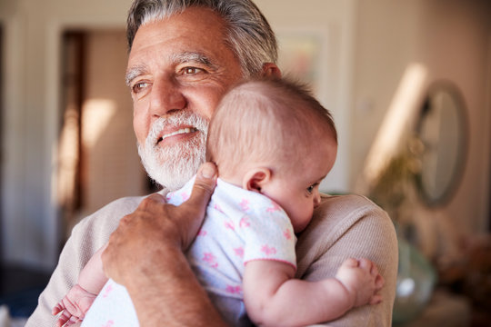 Hispanic Grandfather Holding His Baby Grandson, Head And Shoulders, Close Up