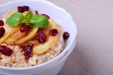 Porridge with caramelized apples and dried cranberries topped with mint