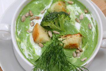 Soup puree with broccoli in white soup stock on a wooden background