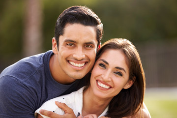 Young Hispanic couple looking to camera smiling, close up