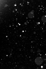 a bokeh of white snow on a black background