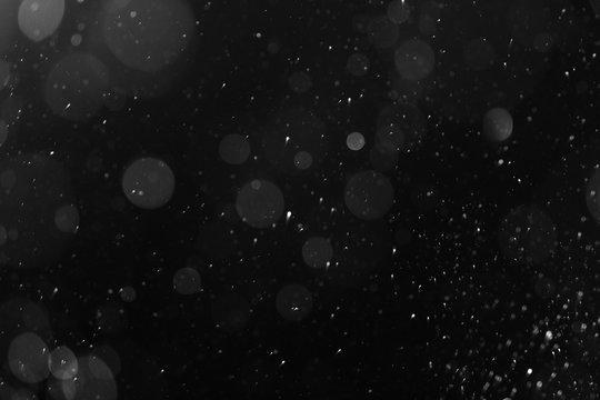 a bokeh of white snow on a black background