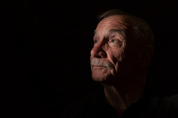 Dark portrait image of senior man, with copy space 