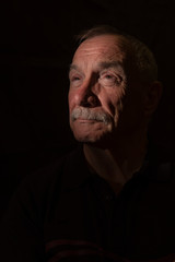 Dark portrait image of senior man, with copy space 