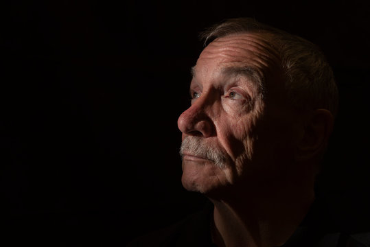 Dark portrait image of senior man, with copy space 