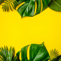 Fototapeta na wymiar Tropical leaves and flowers on yellow background