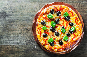 Pizza with Mozzarella cheese, Tomatoes, pepper, olive, Spices and Fresh Basil. Italian pizza. Pizza Margherita or Margarita on wooden table background