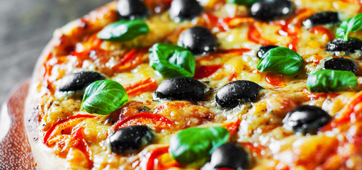 Pizza with Mozzarella cheese, Tomatoes, pepper, olive, Spices and Fresh Basil. Italian pizza. Pizza Margherita or Margarita on wooden table background