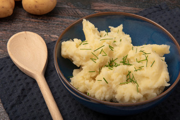 Bowl of mash potatoes with a wooden spoon 