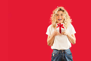 girl with a white gift in her hands on a red isolated background in full growth.Concept for lovers day, Valentine's Day concept