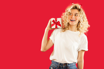 girl with a white gift in her hands on a red isolated background in full growth.Concept for lovers day, Valentine's Day concept