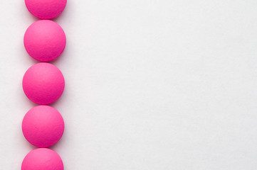 Pink pills in a row on a white background.