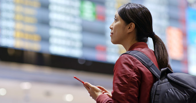 Woman use of mobile phone to check the flight number in the airport