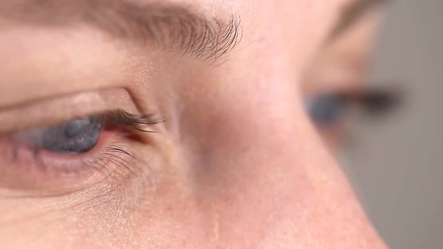 Gray-blue pupil of a young girl moves left, right, watching some movement or reading