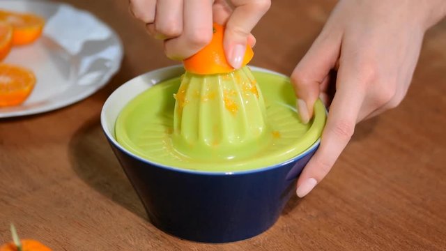 Female hand squeeze the juice out of tangerines.