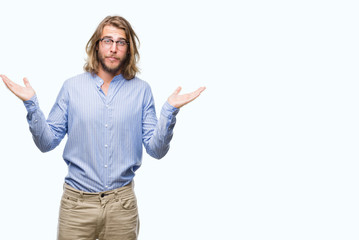 Young handsome man with long hair wearing glasses over isolated background clueless and confused expression with arms and hands raised. Doubt concept.