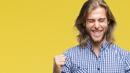 Young handsome man with long hair over isolated background very happy and excited doing winner gesture with arms raised, smiling and screaming for success. Celebration concept.