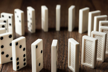 Creative background, white domino, on brown wooden background. Concept of domino effect, chain reaction, risk management, copy space.
