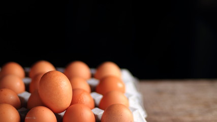 Brown eggs in carton box on dark background