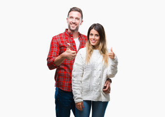 Young couple in love wearing winter sweater over isolated background doing happy thumbs up gesture with hand. Approving expression looking at the camera with showing success.