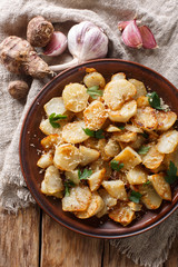 Spicy fried Jerusalem artichoke with garlic, cheese and parsley closeup on a plate. Vertical top view