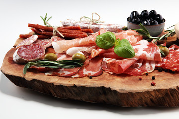 Marble cutting board with prosciutto, bacon, salami and sausages on wooden background. Meat platter