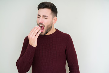 Young handsome man wearing a sweater over isolated background bored yawning tired covering mouth with hand. Restless and sleepiness.