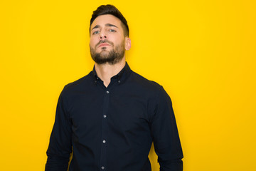 Young handsome man possing and modeling over yellow isolated background
