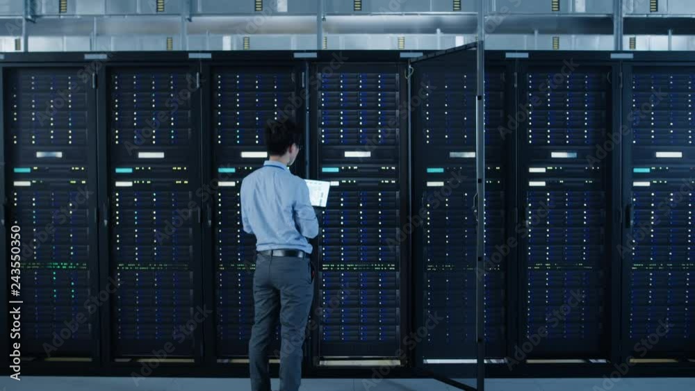 Poster in the modern data center: it engineer standing beside open server rack cabinets, does wireless main