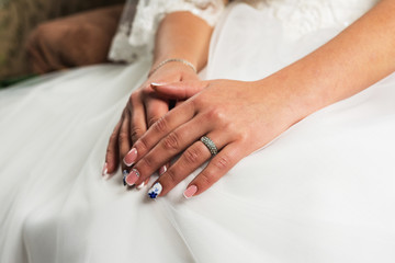 Obraz na płótnie Canvas Closeup of hands of young female person, woman, bride in wedding dress, sitting by window, white curtains with engagement diamond ring on finger of hands