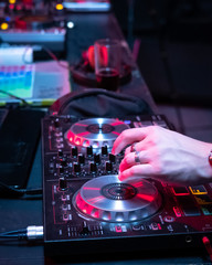 Naklejka premium DJ music console and laptops in bright colors of light in night club bright background