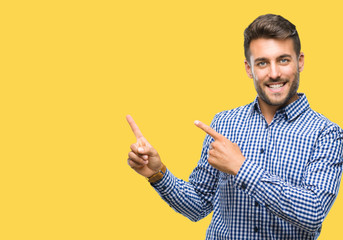 Young handsome man over isolated background smiling and looking at the camera pointing with two hands and fingers to the side.