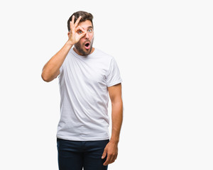 Young handsome man over isolated background doing ok gesture shocked with surprised face, eye looking through fingers. Unbelieving expression.