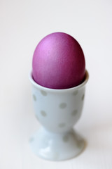 Lila Osterei in weißem Porzellanbecher mit zarter Dekoration