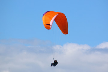 Paraglider flying orange wing